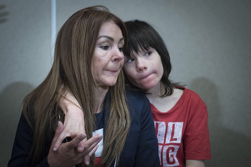 FILE - In this June 11, 2018 file photo, Billy Caldwell sits with his mother Charlotte. Former British Foreign Secretary William Hague called Tuesday, June 19 for the government to take steps toward legalizing marijuana. Hague changed his public stance on cannabis policy days after the government relented and allowed a 12-year-old epileptic boy to receive cannabis oil treatment that his mother said was needed to prevent life-threatening seizures. Home Secretary Sajid Javid said he was convinced after talking to clinicians that the boy, Billy Caldwell, faced a medical crisis.(Stefan Rousseau/PA via AP, File)