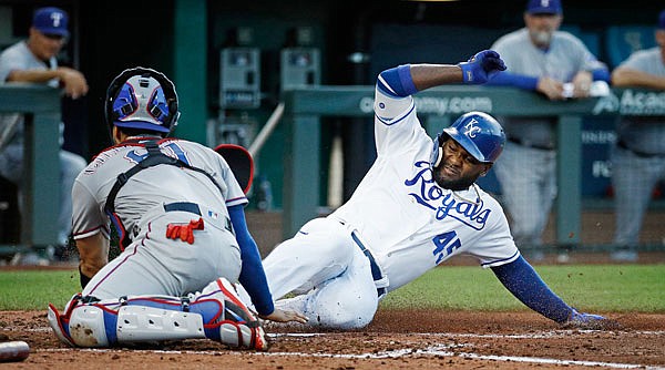 Abraham Almonte of the Royals beats the tag by Rangers catcher Robinson Chirinos to score on a double by Adalberto Mondesi during the third inning of Monday night's game at Kauffman Stadium.