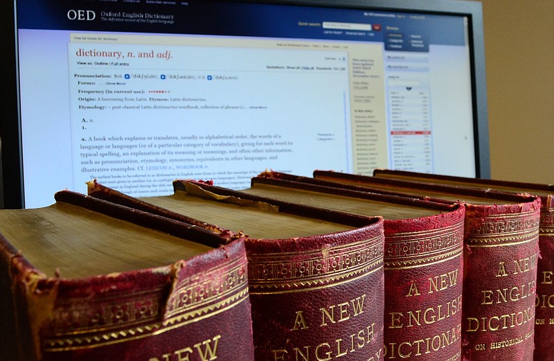 This undated image released by the Oxford English Dictionary shows old volumes of the dictionary next to the a computer monitor displaying a page from the Oxford English Dictionary website. The Oxford English Dictionary has added about 1,000 new entries. (Oxford English Dictionary via AP)