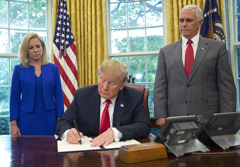 President Donald Trump signs an executive order to keep families together at the border, but says that the 'zero-tolerance' prosecution policy will continue, during an event in the Oval Office of the White House in Washington, Wednesday, June 20, 2018. Standing behind Trump are Homeland Security Secretary Kirstjen Nielsen, left, and Vice President Mike Pence. (AP Photo/Pablo Martinez Monsivais)