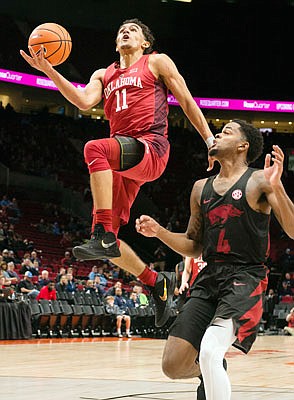 Trae Young of Oklahoma scores a basket against the defense of Daryl Macon of Arkansas during a game last season in Portland, Ore.