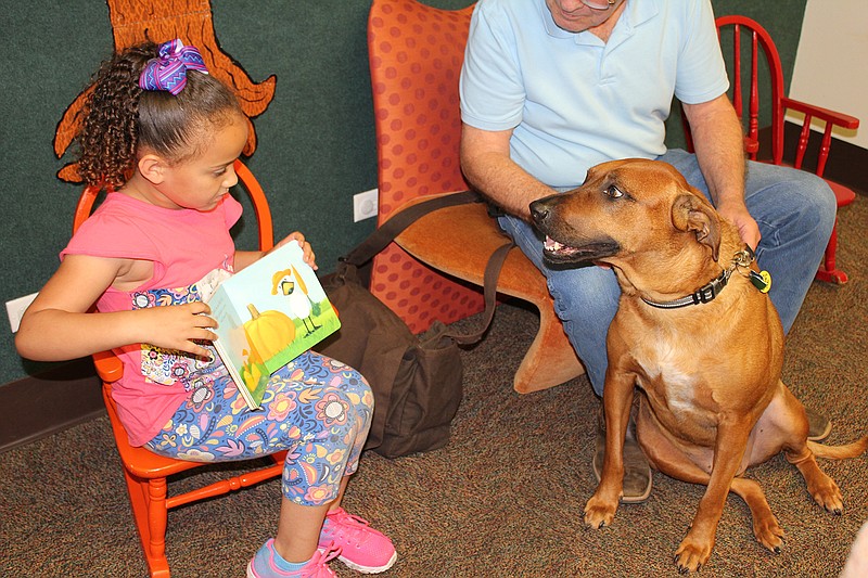 Five-year-old Destiny Vincent, left, shows a book to therapy dog Duke, held by his owner John Whittemore, Tuesday at Texarkana Public Library. Duke has temporarily taken over as the therapy dog for the library's Pages with Poochie program, which encourages children to read by providing a friendly dog to be their audience. The program's previous dog, Sketti, recently retired because of health problems. The library is seeking a permanent replacement. For information, call the library at 903-794-2149.