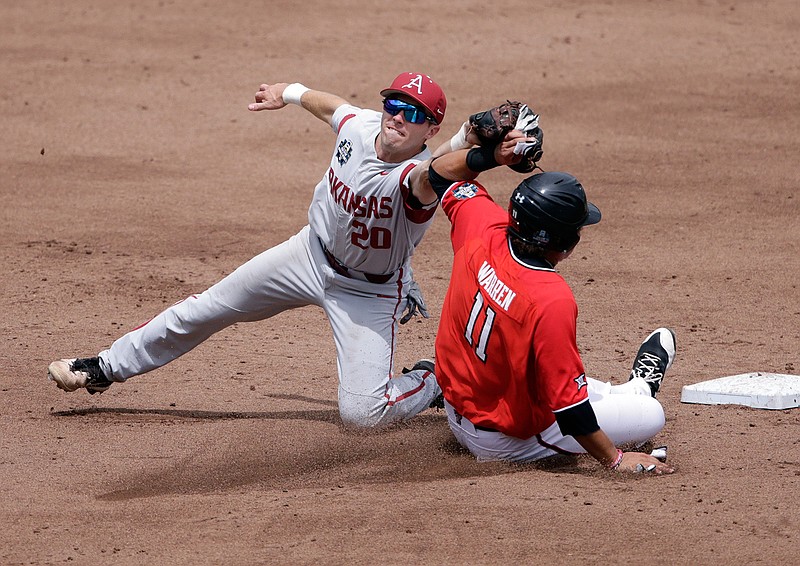 Texas Tech's Cameron Warren (11) is caught stealing second base by Arkansas second baseman Carson Shaddy (20) in the second inning of an NCAA College World Series baseball game Wednesday in Omaha, Neb.