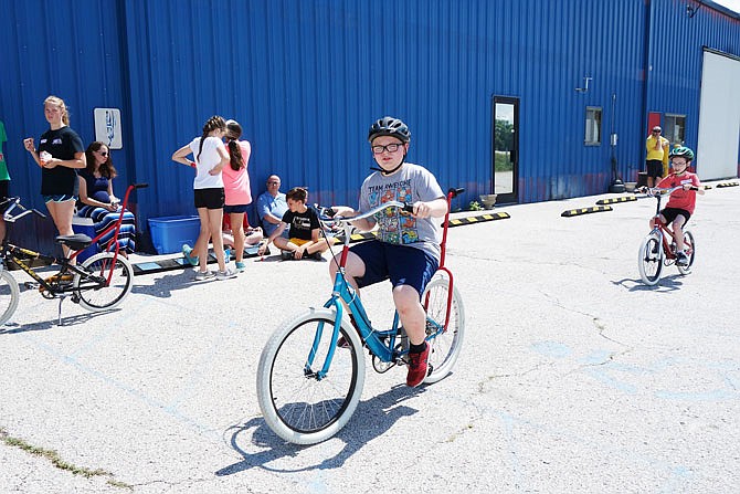 Collin Schrell zips past volunteers during iCan Bike Camp in Fulton. The annual camp, which ran Monday through today, helps children and adults learn to ride bikes.