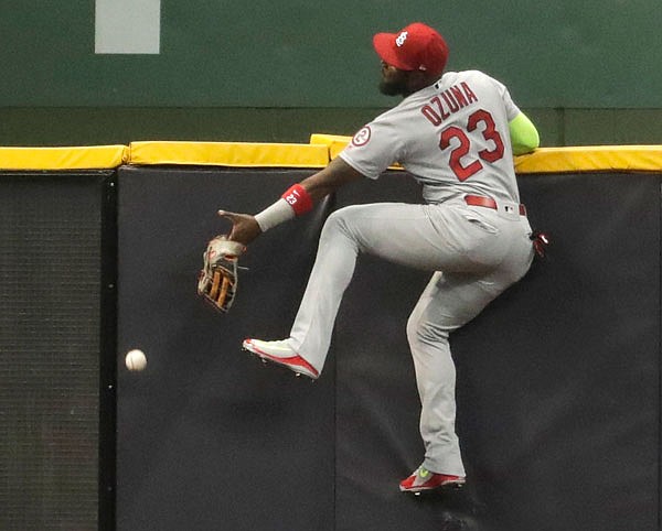 Cardinals outfielder Marcell Ozuna attempts to catch a fly ball in left field during the first inning of Thursday night's game in Milwaukee.