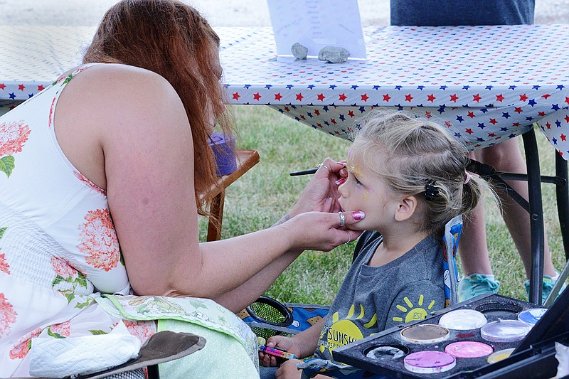 Cora Couf, 3, gets her face painted by Heathora Keith with Forest Dragon Face Painting Friday June 22, 2018 during the annual Tebbetts Comunity Picnic. Heathora and her family traveled from Fulton to set up a face painting booth at the picnic. 