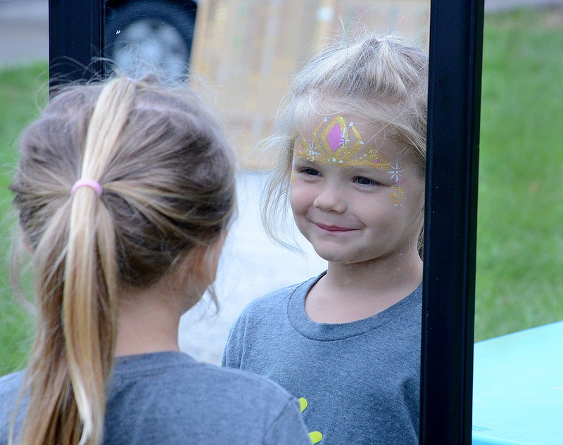 
Cora Couf, 3, smiles at her reflection after getting her face painted Friday June 22, 2018. Cora and her family also enjoyed other activities for kids such as a rubber duck pond game and a carnival car ride. 