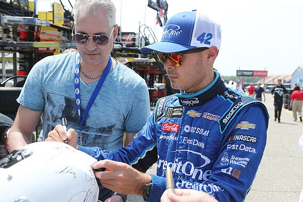 Kyle Larson signs an autograph after a practice session earlier this month in Brooklyn, Mich.