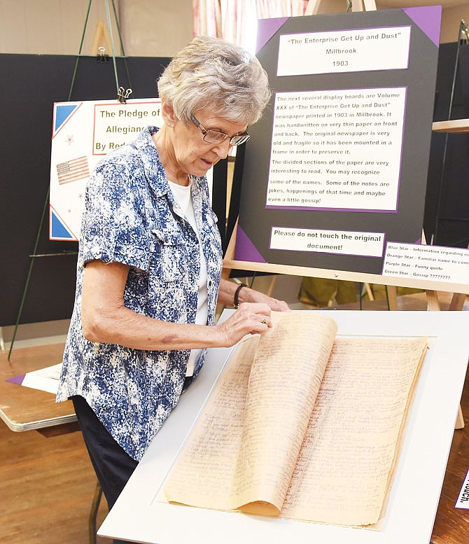 In this June 2018 photo, Patty Ott shows off the original copy of "The Enterprise Get Up and Dust" newspaper from 1903 as part of public displays that several volunteers assembled to promote the history of their beloved Lohman and the Lohman Community Center. 