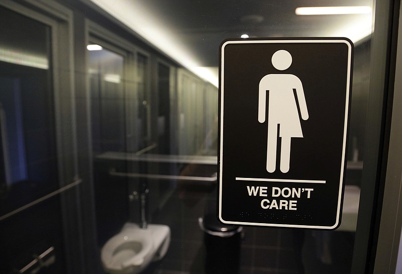 FILE - In this May 12, 2016, file photo, signage hangs outside a restroom at 21c Museum Hotel in Durham, N.C. Transgender plaintiffs who think the compromise that replaced North Carolina's "bathroom bill" is still discriminatory are heading to court. A federal judge will hear arguments Monday, June 25, 2018, from lawyers representing Republican legislative leaders who say the case should be dismissed because the plaintiffs can't prove the new law is harming them. (AP Photo/Gerry Broome, File)