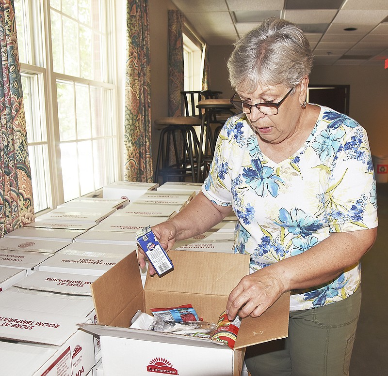 Barb Slevin shows the items in the pre-packaged food boxes that will be sent home with children so they'll have plenty to eat for the weekend. Slevin is volunteering with the Food 4 Kids program at First Presbyterian Church.