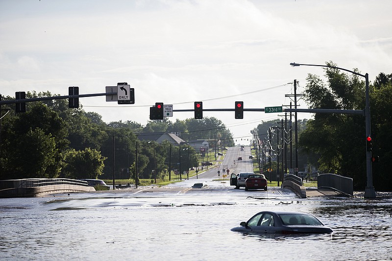 Two men sit stranded in their cars, surrounded by flood water from Fourmile Creek on the bridge at the intersection of Hubbell Avenue and East 33rd Street on Des Moines' east side on Sunday morning, July 1, 2018 after heavy rain fell overnight. The creek crested at a record 17.47 feet around 6:00 a.m. (Kelsey Kremer/The Des Moines Register via AP)