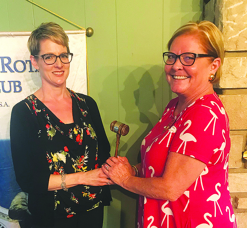 Outgoing Rotary Club President Jennifer Books, left, presents a gavel to incoming Club President Debbie Laughlin. 