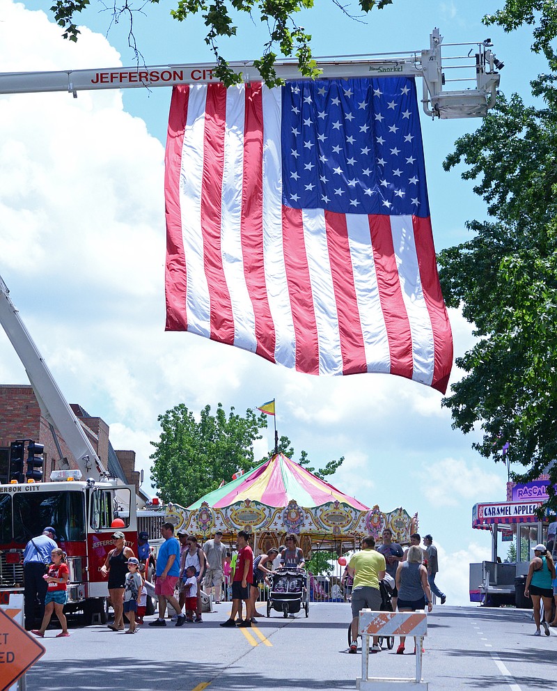
Visitors look at a fire truck hanging a giant flag  July 4, 2018, at the annual Salute to America event in downtown Jefferson City. The fire truck and other service vehicles allowed children and families to learn more about how service men and women use the equipment in cases of emergency.