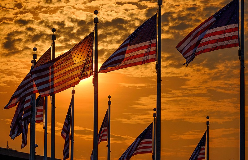 U.S. flags surrounding the Washington Monument are backlit by the rising sun on Independence Day, Wednesday, July 4, 2018, in Washington. (AP Photo/J. David Ake)