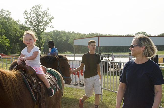 Marlee Fauthn, left, rides a pony as Julie Borgmayer supervises during Holts Summit's Independence Day celebration.