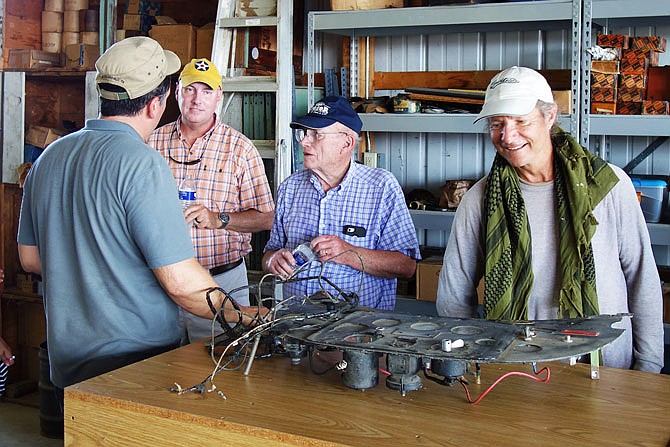 Mechanic Harman Dickerson, center, walks Travel Air enthusiasts through his hangar full of aircraft parts — such as the old instrument panel in front of him. Dickerson is a top expert in the vintage planes, which were built in the late 1920s.
