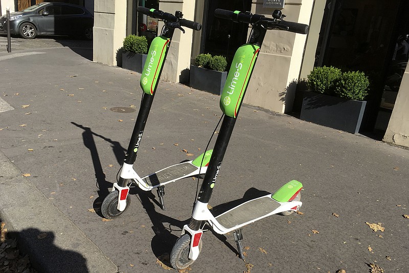 This July 3, 2018, photo shows scooters by Lime in Paris. Uber is getting into the scooter-rental business. The ride-hailing company said Monday, July 9, that it is investing in Lime, a startup based in San Mateo, California. (AP Photo/Michel Euler)