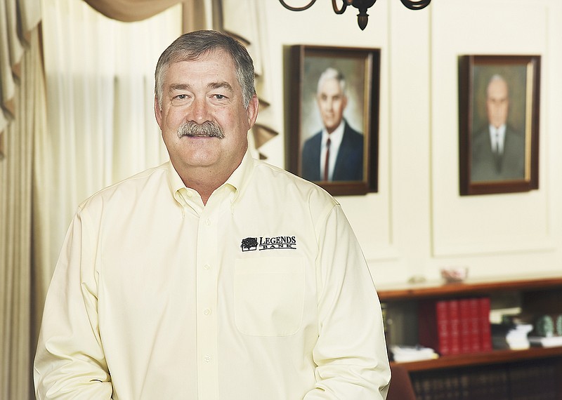 John Klebba stands in the conference room at Legends Bank in Linn. In the background are portraits of the bank's co-founders, his grandfather John Klebba and the elder Klebba's brother-in-law, Herman Fick. 