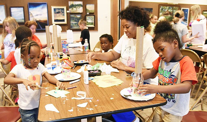 Zariah Peoples, left, and Teveeon Fowler, concentrate on their craft project while babysitter Pamela Martin joins right in during Tuesday's Trash to Treasure Day at Missouri River Regional Library.