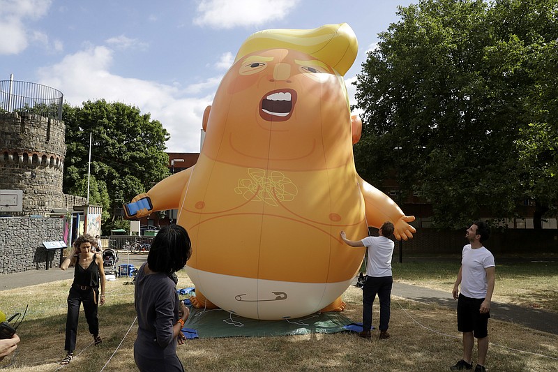 In this photo taken on Tuesday, July 10, 2018,  a six-meter high cartoon baby blimp of U.S. President Donald Trump stands inflated during a practice session in Bingfield Park, north London. Trump will get the red carpet treatment on his brief visit to England that begins Thursday: Military bands at a gala dinner, lunch with the prime minister at her country place, then tea with the queen at Windsor Castle before flying off to one of his golf clubs in Scotland. But trip planners may go out of their way to shield Trump from viewing another aspect of the greeting: an oversize balloon depicting the president as an angry baby in a diaper that will be flown from Parliament Square during what are expected to be massive gatherings of protesters opposed to Trump’s presence. (AP Photo/Matt Dunham)