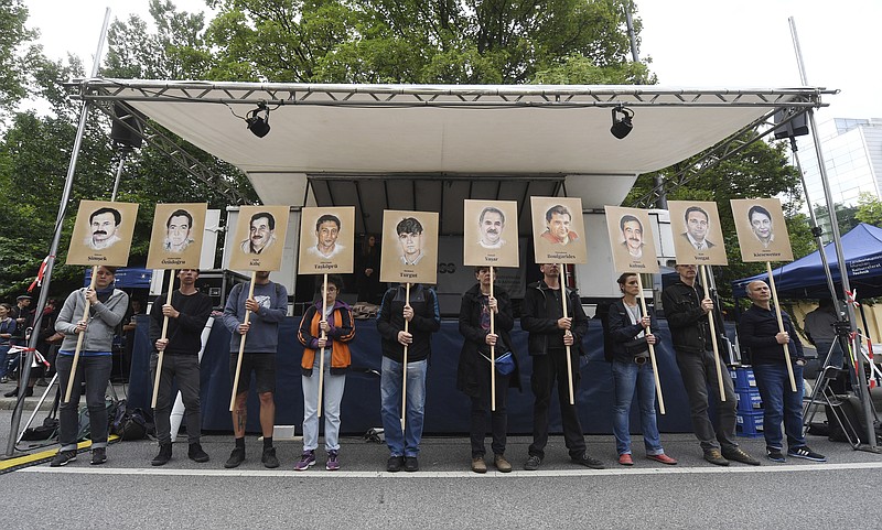 Demonstrators hold signs with people killed by the NSU outside the court in Munich, southern Germany, prior to the verdict Wednesday, July 11, 2018. (Tobias Hase/dpa via AP)