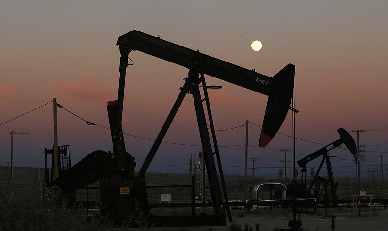 FILE - In this June 8, 2017, file photo, oil derricks are busy pumping as the moon rises near the La Paloma Generating Station in McKittrick, Calif. The U.S. is on pace to leapfrog both Saudi Arabia and Russia as the world’s biggest oil producer. (AP Photo/Gary Kazanjian, File)