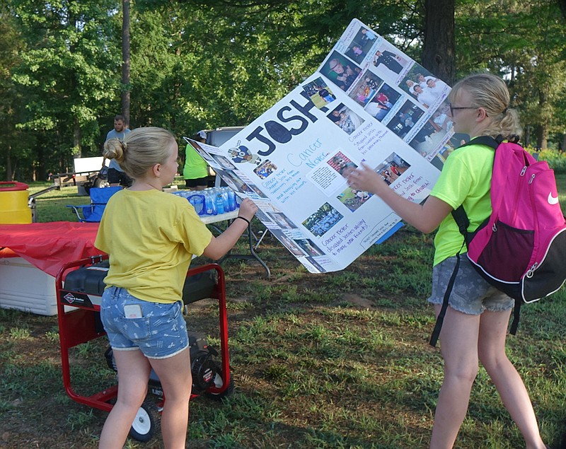  Caylee Fuller, 12, left, and Nevaeh Arnold, 13, take out the sign Nevaeh made to support her brother Josh during the Fight Like A Champion community benefit held Saturday at Linden City Park.
