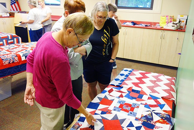 Members of the quilting group that meets at the Callaway County Public library look over quilts in progress brought by Mid-Missouri Quilts of Valor. Each is customized for the veteran who will receive it.

