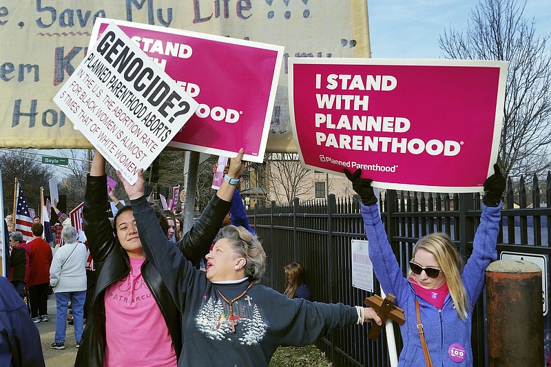 FILE - In this Feb. 11, 2017, file photo, a Planned Parenthood supporter and opponent try to block each other's signs during a protest and counter-protest of abortion in St. Louis. If a Supreme Court majority shaped by President Donald Trump overturns or weakens the right to abortion, the fight over its legalization could return to the states. (AP Photo/Jim Salter, File)