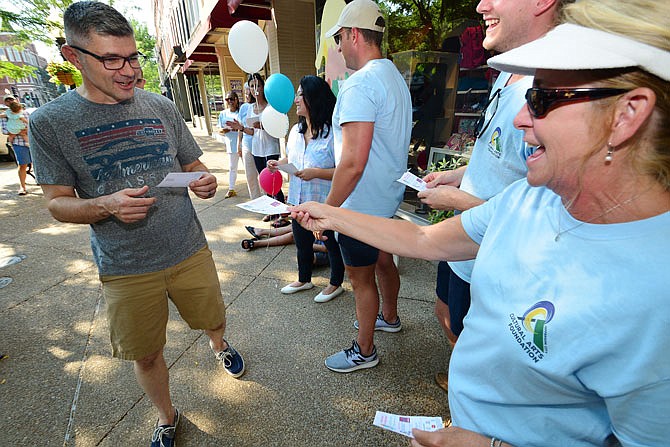 Jefferson City Cultural Arts Foundation and Ice Cream Splash Special Committee volunteers pass out flyers Wednesday to Guy Van Drunen outside Carrie's Hallmark to publicize Friday evening's Ice Cream Splash event. Carrie's is selling tickets as well.