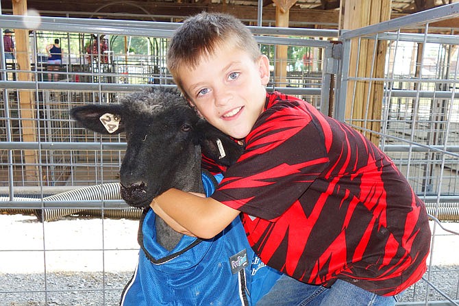 Luke Riecke, 9, hugs Tucker the sheep before the goat and sheep show Wednesday at the Callaway Youth Expo. According to Riecke, Tucker hates everyone except him.
