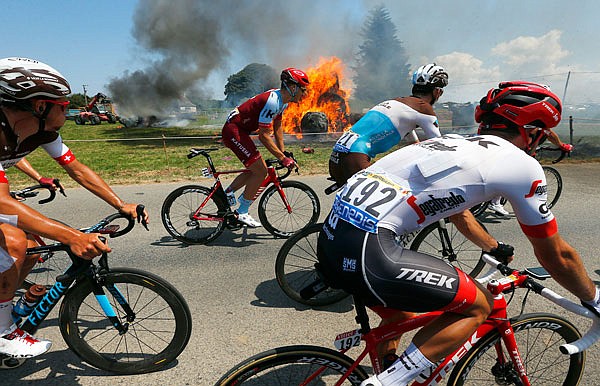 The pack rides past a burning haystack during Thursday's sixth stage of the Tour de France.