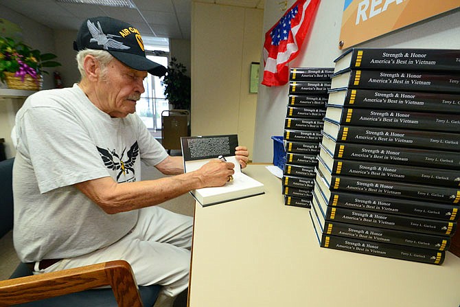 Melvin Gregory, a Vietnam veteran, signs the book, "Strength and Honor: America's Best in Vietnam" on Friday at the Missouri River Regional Library annex.