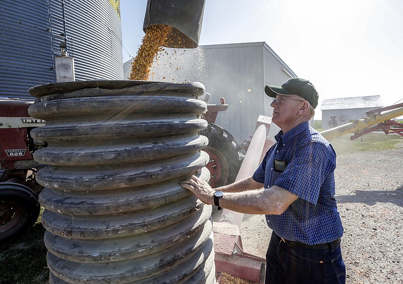 In this July 12, 2018 photo, farmer Don Bloss checks on the operation of an auger transferring corn on his farm in Pawnee City, Neb. Farmers and agricultural economists are worried that president Donald Trump’s trade, immigration and biofuels policies will cost farms billions of dollars in lost income and force some out of business. Bloss, who grows corn, soybeans, sorghum and wheat on his farm in the southeastern Nebraska community of Pawnee City, said he’s already seen a few neighbors quit farming as they struggled to make a profit even before the tariff battle began this year. (AP Photo/Nati Harnik)