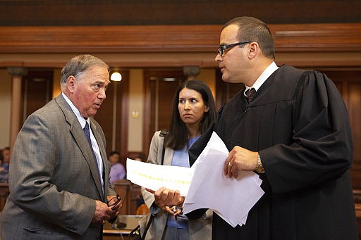 In this June 6, 2018 photo, local attorney Tali Villafranca, left, and Assistant District Attorney Jacquelyn Johnson talk with Judge Eli Garza before he addresses prospective jurors in Victoria, Texas. Victoria County summoned about 100 residents to make up two 12-member juries in mid-June. (Evan Lewis/The Victoria Advocate via AP)