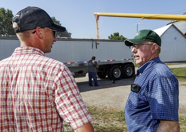 In this July 12, 2018 photo, farmer Don Bloss, right, talks to his son Mark as a grain truck is being loaded with corn in Pawnee City, Neb. Farmers and agricultural economists are worried that president Donald Trump's trade, immigration and biofuels policies will cost farms billions of dollars in lost income and force some out of business. (AP Photo/Nati Harnik)