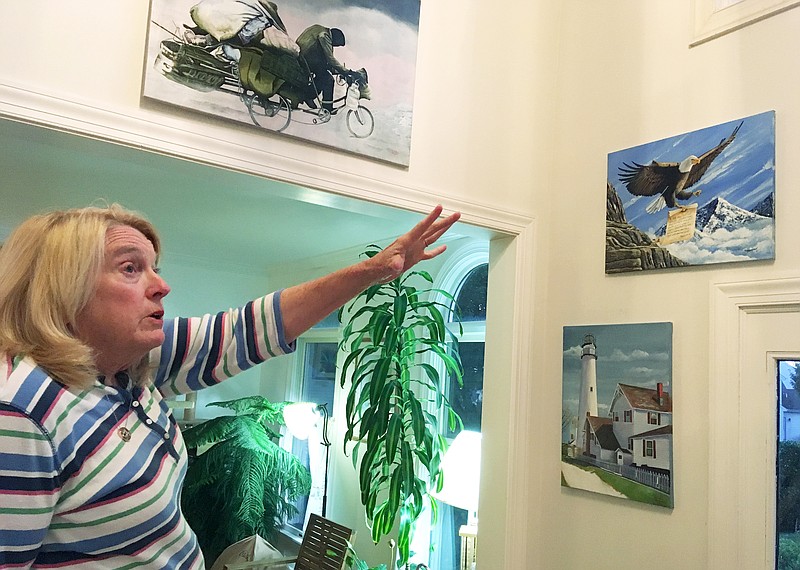 Former Department of Correction counselor Patricia May describes some of the many paintings by Delaware prison inmates that decorate her home in Hockessin, Del., Monday, July 16, 2018. May, a state corrections counselor who was taken hostage during a deadly riot at Delaware's maximum-security prison, says prison officials are to blame. On Tuesday, Gov. John Carney and corrections officials will release a final report on efforts to implement 41 recommendations from an independent review team. (AP Photo/Ransall Chase)