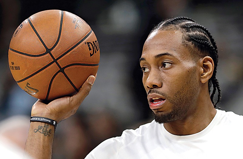 In this Jan. 5, 2018, file photo, San Antonio Spurs forward Kawhi Leonard handles a ball before an NBA basketball game against the Phoenix Suns in San Antonio. Two people familiar with the situation say San Antonio and Toronto have reached an agreement in principle on a trade that will send Kawhi Leonard to the Raptors and DeMar DeRozan to the Spurs. One of the people says the Spurs also are sending Danny Green to the Raptors as part of the deal. Both people spoke to The Associated Press on condition of anonymity Wednesday, July 18, 2018, because the deal has not been finalized. (AP Photo/Eric Gay, File)