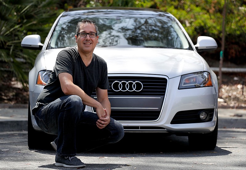 Keith Reynolds, who is on the Tesla waiting list for a Model 3, is photographed  by his 9-year-old Audi A3 compact car Monday, July 16, 2018, in Laguna Hills, Calif. For many on the list to buy Tesla's mass-market electric car, the wait for the company to produce enough to satisfy demand isn't a major problem. But the prospect of losing a U.S. federal tax credit is. (AP Photo/Chris Carlson)