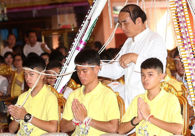 Soccer coach Ekkapol Janthawong, center, and members of the rescued soccer team attend a Buddhist ceremony that is believed to extend the lives of its attendees as well as ridding them of dangers and misfortunes in Mae Sai district, Chiang Rai province, northern Thailand, Thursday, July 19, 2018. The 12 boys and their soccer coach rescued from a cave in northern Thailand left the hospital where they had been recuperating and appeared at a news conference Wednesday, saying the ordeal made them stronger and taught them not to live carelessly. (AP Photo/Sakchai Lalit)