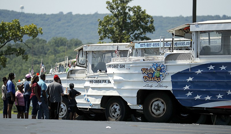 People view a row of idled duck boats in the parking lot of Ride the Ducks Saturday, July 21, 2018 in Branson, Mo. One of the company's duck boats capsized Thursday night, July 19, resulting in several deaths on Table Rock Lake. (AP Photo/Charlie Riedel)