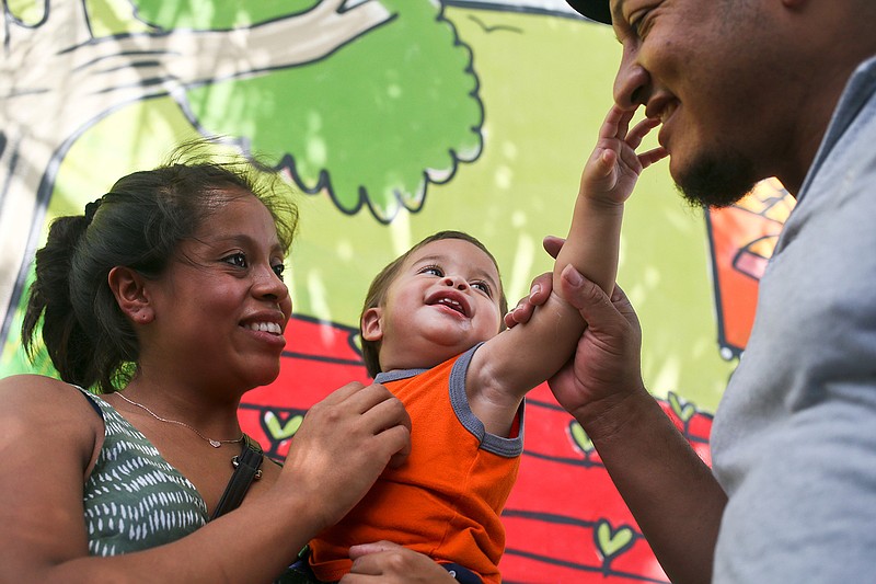 Adalicia Montecino holds her year-old son Johan Bueso Montecinos, who became a poster child for the U.S. policy of separating immigrants and their children, as Johan touches his father Rolando Bueso Castillo's face, in San Pedro de Sula, Honduras, Friday, 20, 2018. Johan Bueso Montecinos arrived in San Pedro Sula and was reunited with his parents on a government bus. Captured by Border Patrol agents in March, Johan's father was deported and the then 10-month-old remained at an Arizona shelter. (AP Photo/Esteban Felix)
