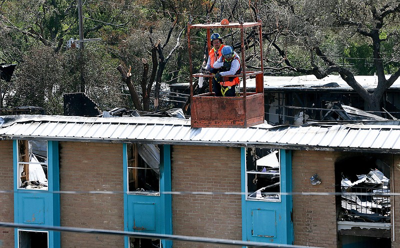 Fire officials are lowered in a basket by a crane outside Building 500 on Monday at the apartment complex.
Marvin Pfeiffer/
The San Antonio Express-News via AP