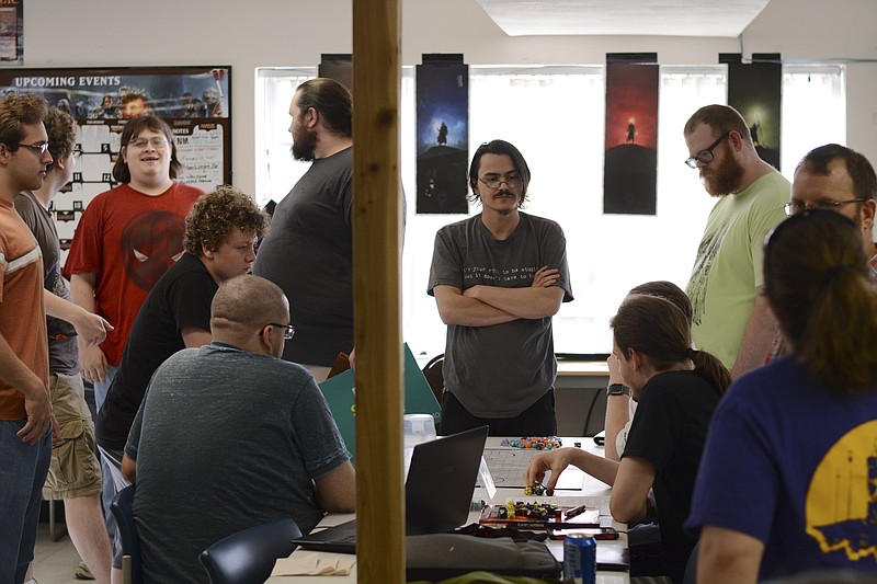 Jesse Peterson, center, stands over a game of Dungeons & Dragons at Capital City Game Emporium. Peterson has been organizing the weekly D&D games at Capital City for the last five years.