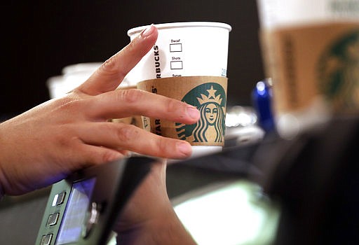 FILE - In this May 29, 2018, file photo, a barista reaches for an empty cup at a Starbucks in the Pike Place Market in Seattle. Starbucks and other employers in California must pay workers for minutes they routinely spend off the clock on tasks such as locking up or setting the store alarm, the state Supreme Court ruled Thursday, July 26, 2018. The unanimous ruling was a big victory for hourly workers in California and could prompt additional lawsuits against employers in the state. (AP Photo/Elaine Thompson, File)