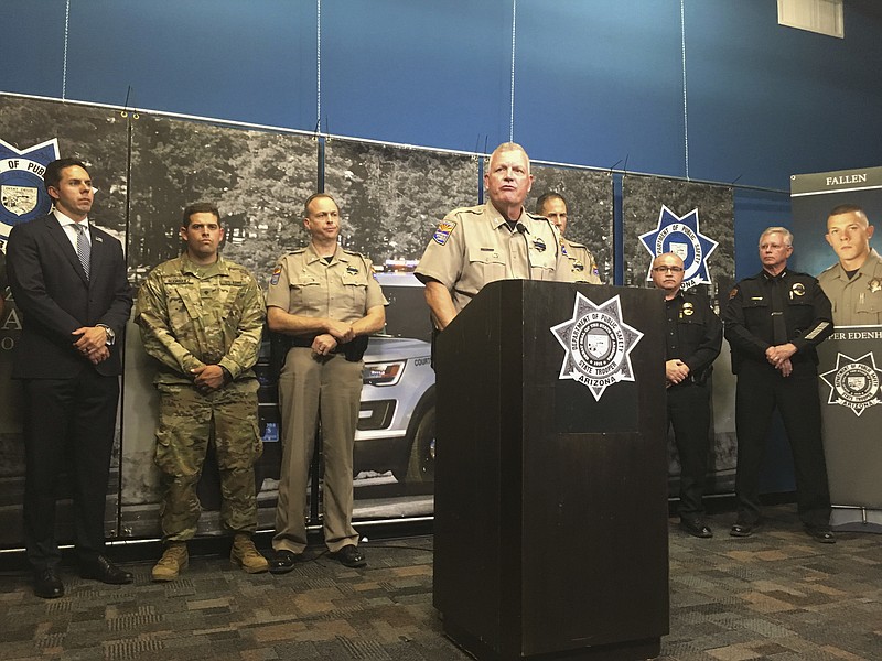 Arizona Department of Public Safety Director Col. Frank Milstead speaks at a news conference in Phoenix on Thursday, July 26, 2018, while flanked by officers and a picture of slain DPS Trooper Tyler Edenhofer. Authorities say a male suspect used a state trooper's gun and fatally shot Edenhofer and wounded another trooper Wednesday night after reports of someone throwing rocks at vehicles. (AP Photo/Terry Tang)