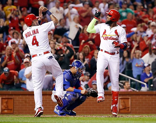 Marcell Ozuna (right) celebrates with Cardinals teammate Yadier Molina after hitting a two-run home run during the first inning of Sunday night's game against the Cubs at Busch Stadium.