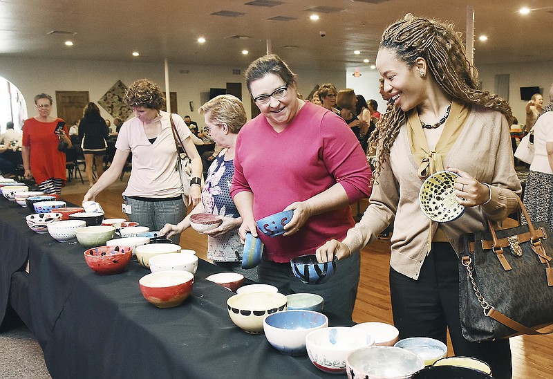 Ashley Ray, right, and Shawna Blight try to settle on a bowl Tuesday, July 31, 2018, while waiting in line to get soup. The pair work in downtown Jefferson City and were just a couple of the hundreds who attended the third annual Empty Bowls fundraiser for The Salvation Army Center of Hope.