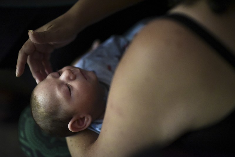 In this Dec. 16, 2016 file photo, Puerto Rico resident Michelle Flandez caresses her two-month-old son Inti Perez, diagnosed with microcephaly linked to the mosquito-borne Zika virus, in Bayamon, Puerto Rico. In the first long-term look at what happened to children of U.S. mothers who were infected with Zika during pregnancy, one in seven developed some kind of health problem _ranging from birth defects to conditions that became apparent only later. Health officials released the findings Tuesday, Aug. 7, 2018. (AP Photo/Carlos Giusti)